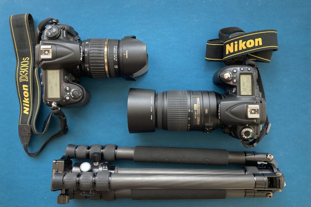 Nikon Kamera D300s (links) und Nikon D90. Die Kamera haben beide Tamron 17-50-2,8 (links) Nikon 55-300 angeschlossen. Unten sieht man ein zusammengeklapptes Fotostativ.